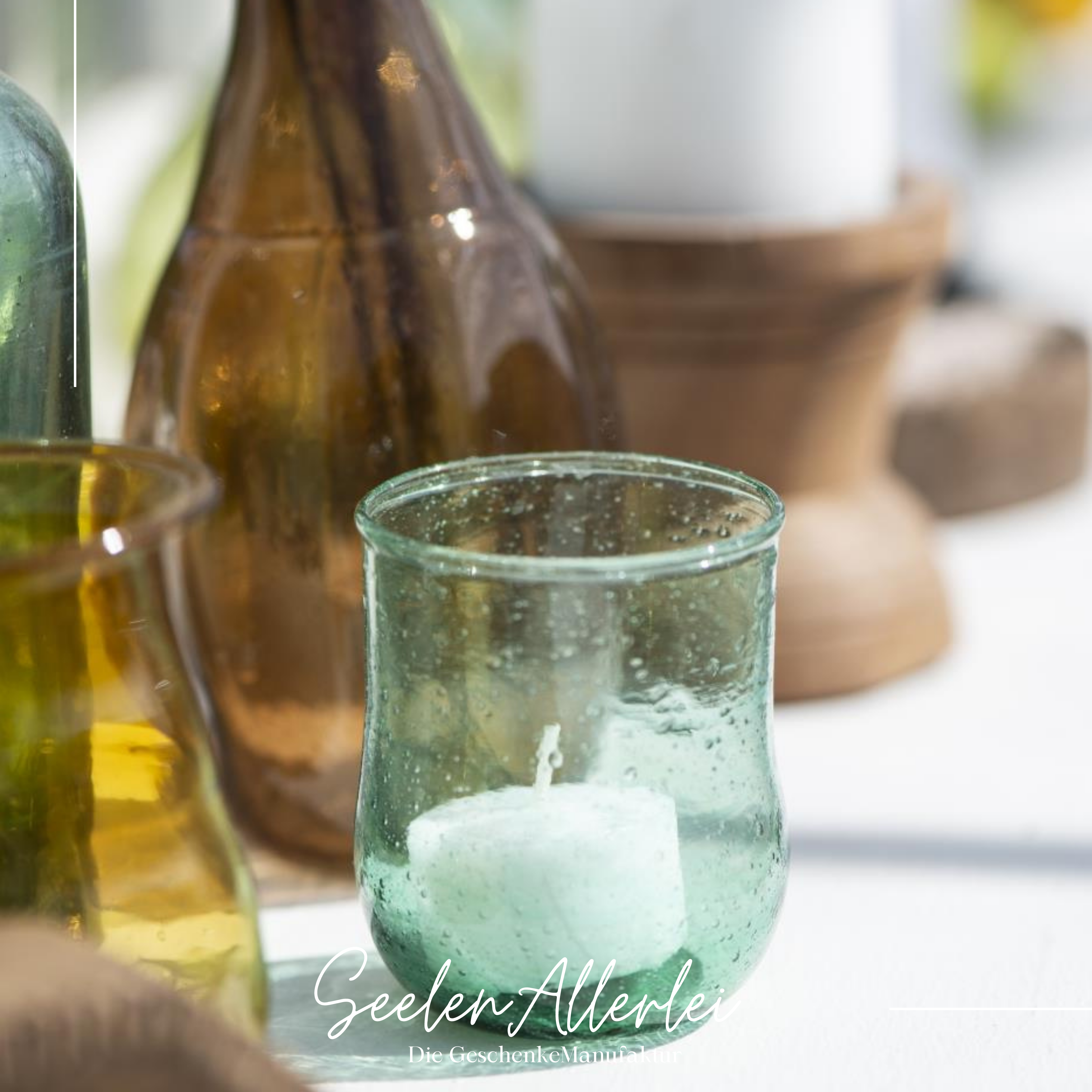 Teelichthalter aus Glas stehen in verschiedenen Farben auf einem Tisch. in manchen ist ein Teelicht 