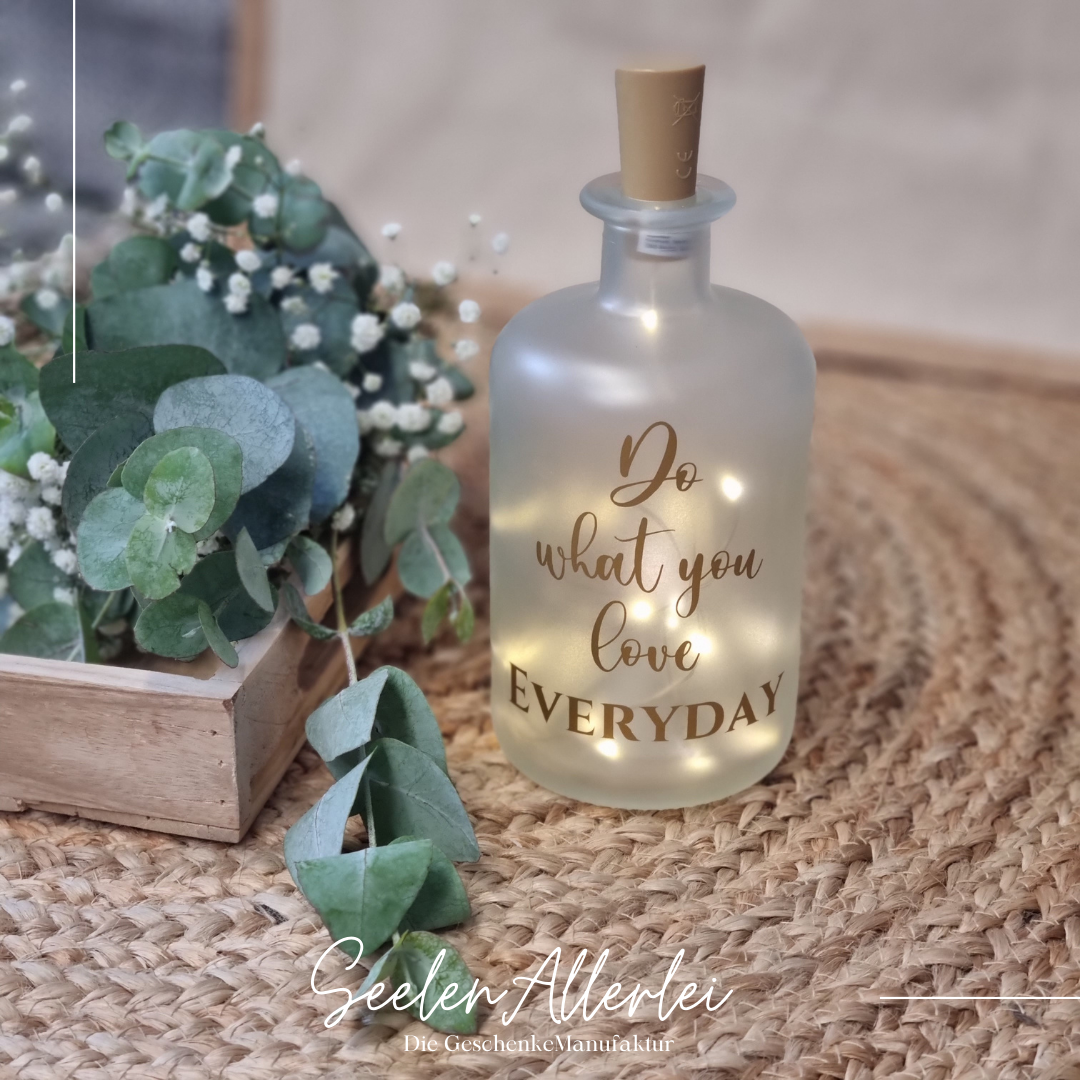 Do what you love steht in goldener Schrift auf einer Apothekerflasche mit Lichterkette